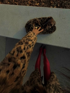 Top-down POV view of luxury leopard faux fur coat and matching handbag with red stockings