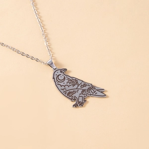 Macro detail of silver raven pendant featuring engraved moon, star, and pumpkin motifs