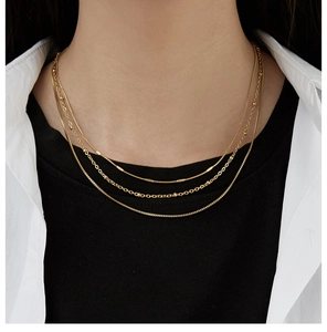 Close-up of gold layered chain necklace set featuring snake, bead, and fine link styles