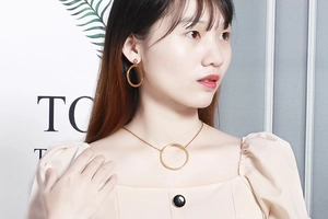 Close-up of a woman wearing a minimalist gold hollow circle necklace and earrings set