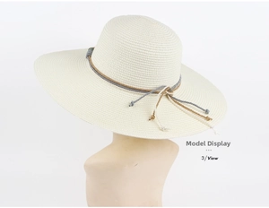 Detailed close-up of cream-colored straw sun hat with woven cord decoration on top