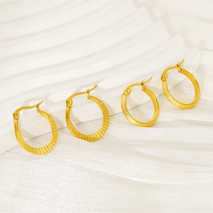 Fashionable gold twisted hoop earrings with spiral texture on white silk background