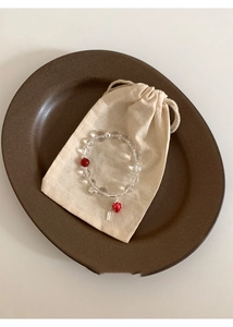 Detail of beaded strawberry bracelet with glass beads and linen jewelry pouch