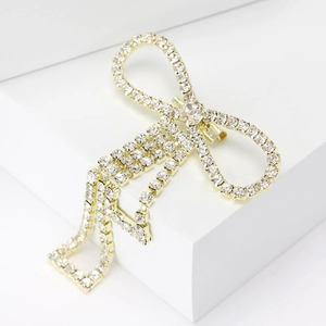 Close-up of sparkling rhinestone bow brooch with golden tassels on a white background