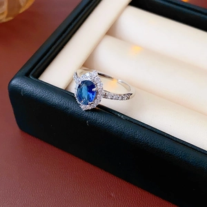 Macro view of a classic silver ring with an oval blue sapphire and white zircon halo