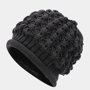 Macro detail of charcoal grey knitted beanie showing thick cable stitch texture and rolled hem