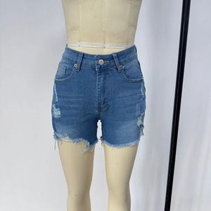 Detail of high waisted blue denim shorts with distressed ripped holes and raw hem edges