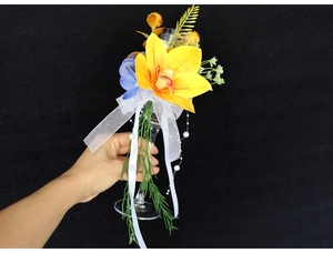 Detail of handmade wedding champagne glass floral decor with yellow cymbidium and ribbon