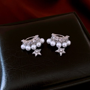 Detail of silver double-layered ear cuff with zircon, pearls and star pendant on black leather