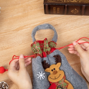 Close-up of a grey felt Christmas gift bag with a 3D reindeer doll and red drawstring