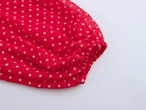 Dettaglio della manica a sbuffo rossa a pois bianchi con polsini elastici sul vestito