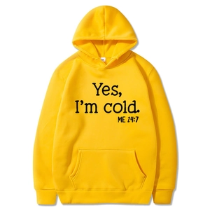 Detail of a bright yellow hoodie featuring bold Yes I'm cold black letter print design