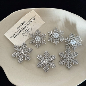Sparkling silver snowflake hair clips with rhinestones and pearls on a ceramic plate