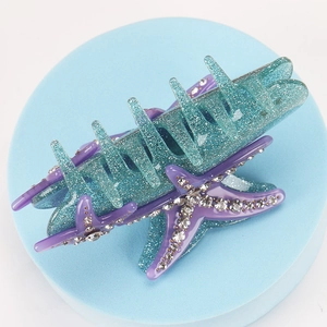 Macro view of blue starfish hair claw with purple glitter and inlaid rhinestones