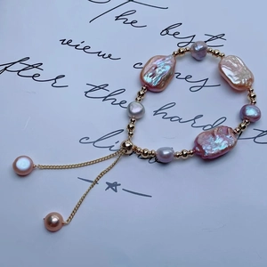 Vista macro di bracciale con perle barocche viola e catena regolabile su carta bianca