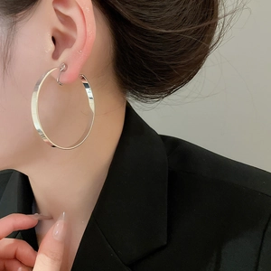 Close-up of minimalist silver hoop earring with high-polish finish on model's ear