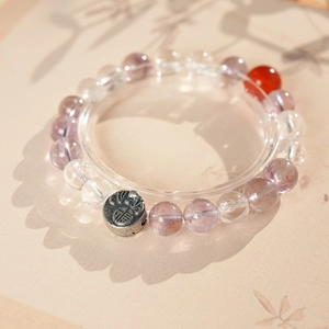 Macro detail of bead bracelet featuring transparent crystals and silver Fu pendant