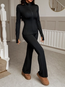Close-up of black Y2K zip-up jacket and flared yoga pants on model in corridor