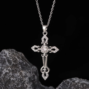 Dettaglio macro della collana a croce gotica d'argento con zirconi su una roccia