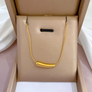 Elegante goldene Titanstahlkette mit glattem zylindrischem Stabanhänger in einer Schmuckbox