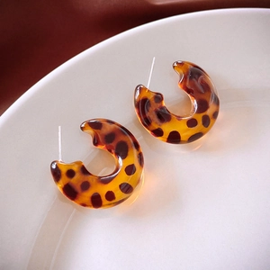 Close-up of leopard print resin C-shaped earrings on white ceramic tray