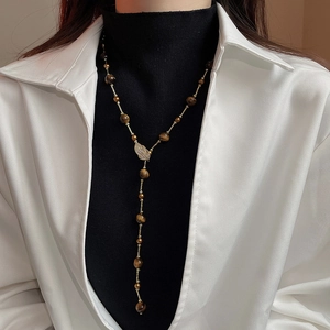 Detail view of Y-shaped necklace with zircon leaf charm and brown tiger eye stone beads