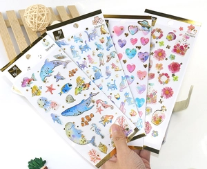 Detail showing four gold-foil stickers including ocean, cat, heart and floral themes