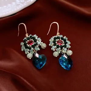 Ethnic beaded flower earrings with blue heart crystal drop on red silk background