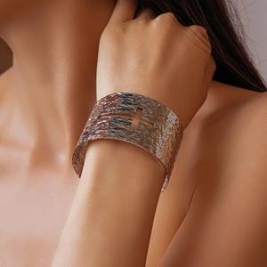 Detail view of silver textured cuff bracelet with hollow cross and rock surface texture