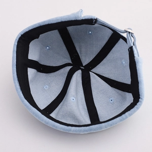 Close-up of light blue denim skull cap interior with black trim and silver buckle