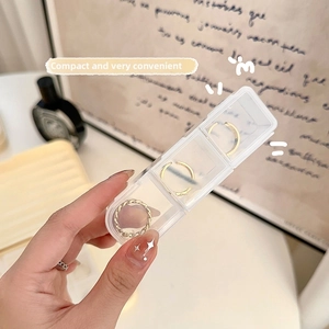 Boîte à bijoux transparente à trois compartiments avec trois bagues dorées à l'intérieur