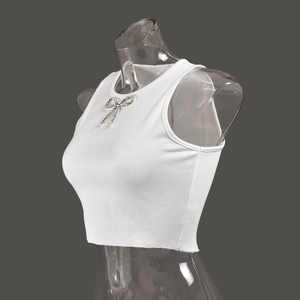 Detail of white ribbed knit crop top featuring a sparkling rhinestone bow decoration