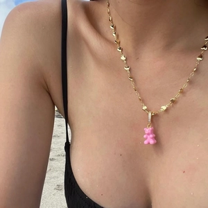 Detail of a pink gummy bear pendant with diamond accents on a gold heart-link chain