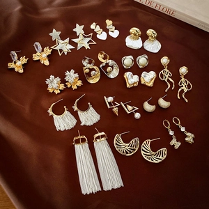 Close-up of gold-plated tassel earrings with star and heart designs on brown silk