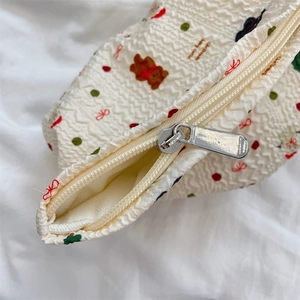 Detailed macro view of silver metal zipper and wave texture on cream bear makeup bag