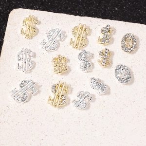 Macro shot of 3D dollar sign nail art charms in gold and silver with micro rhinestones