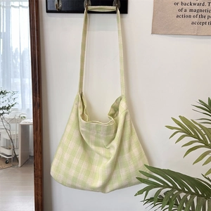 Close-up of light green gingham canvas tote bag hanging on a minimalist wall hook
