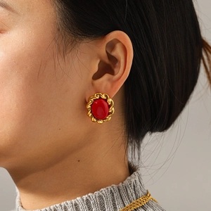 Close-up of vintage gold stud earrings with red gemstone on Asian model