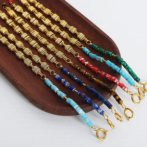 Luxurious gold chain bracelets with colorful natural stones on a wooden tray