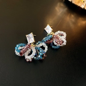 Macro shot of handmade beaded flower earrings with colorful beads and zircon on black leather