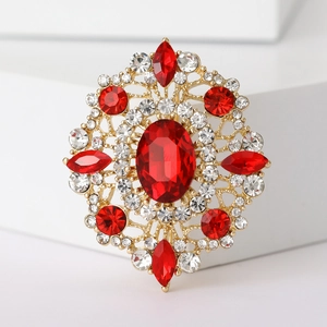 Detail of vintage gold brooch featuring red oval gemstone and sparkling crystal inlay