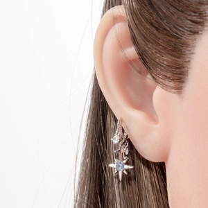 Minimalist silver star clip earring with blue crystals worn on a model's ear