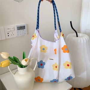 Detail of floral tote bag with thick blue braided rope handles and woven brand label