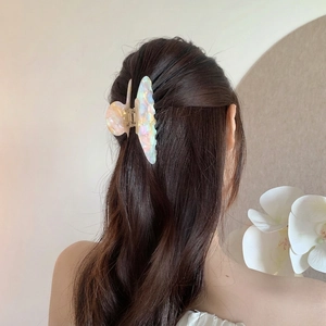 Elegant butterfly hair claw clip with pearlescent finish on a half-up hairstyle