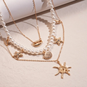 Detail of gold-layered necklace featuring white pearls, starfish and seashell charms