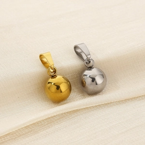 Detailed view of polished gold and silver ball pendants on a soft beige fabric background