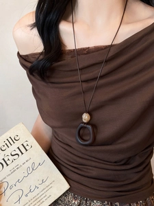 Detail of a vintage resin wood ring pendant necklace on a brown textured top