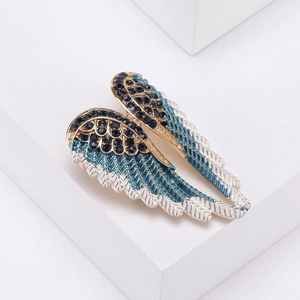 Detailed macro view of crystal-encrusted angel wing brooch with blue gradient feathers