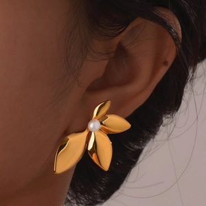 Boucles d'oreilles fleur feuille dorée avec perle blanche portée par un mannequin