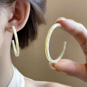 Retro ivory resin C-shaped hoop earrings with marble texture on an elegant model